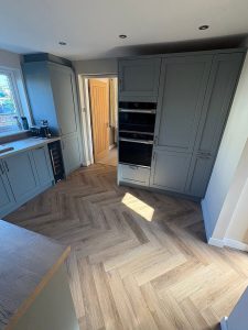 A modern kitchen with a wood floor and stylish blue cabinets, enhancing the overall aesthetic.